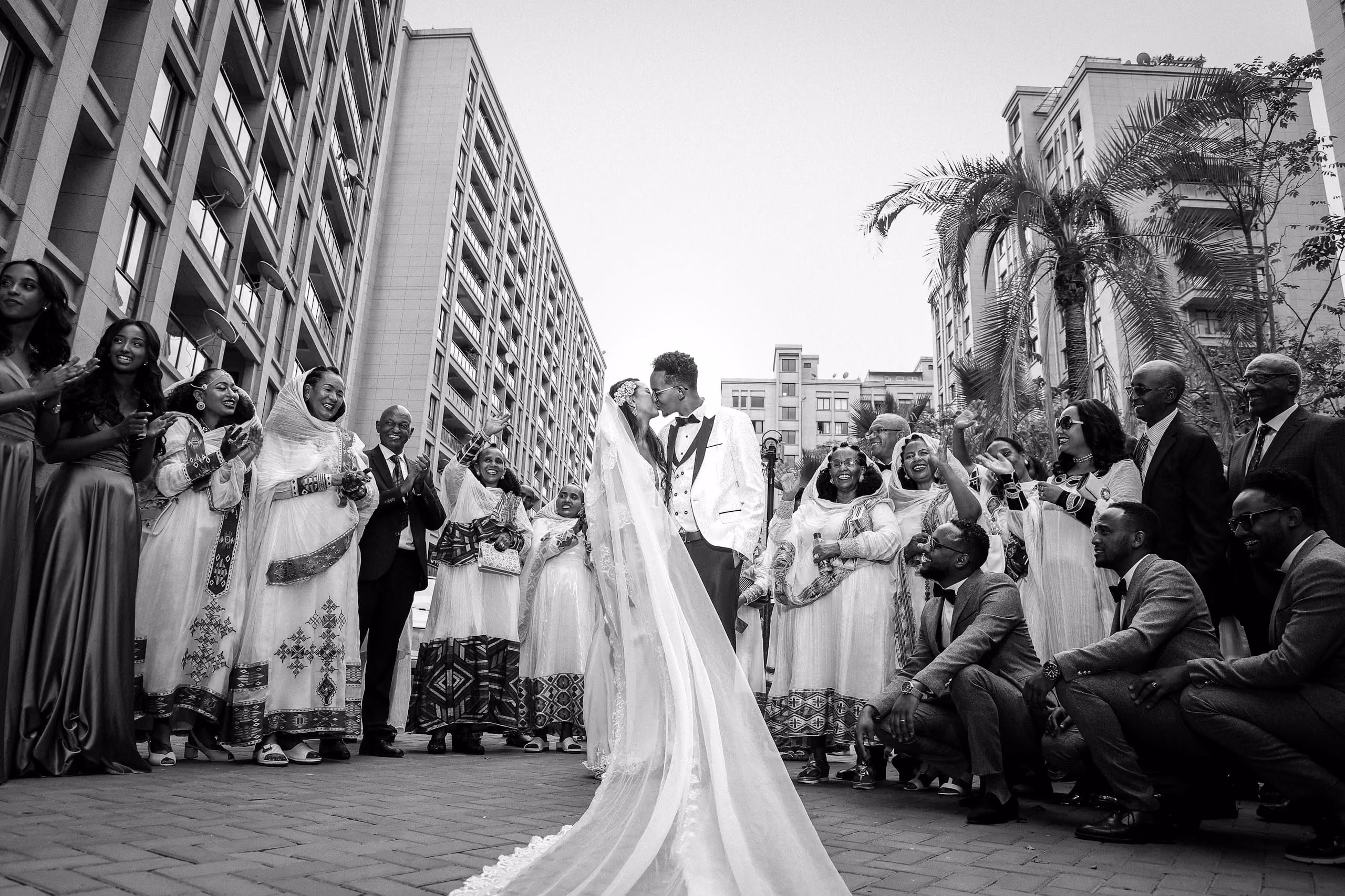 Black and white photo of a bride and groom walking through a crowd of guests
